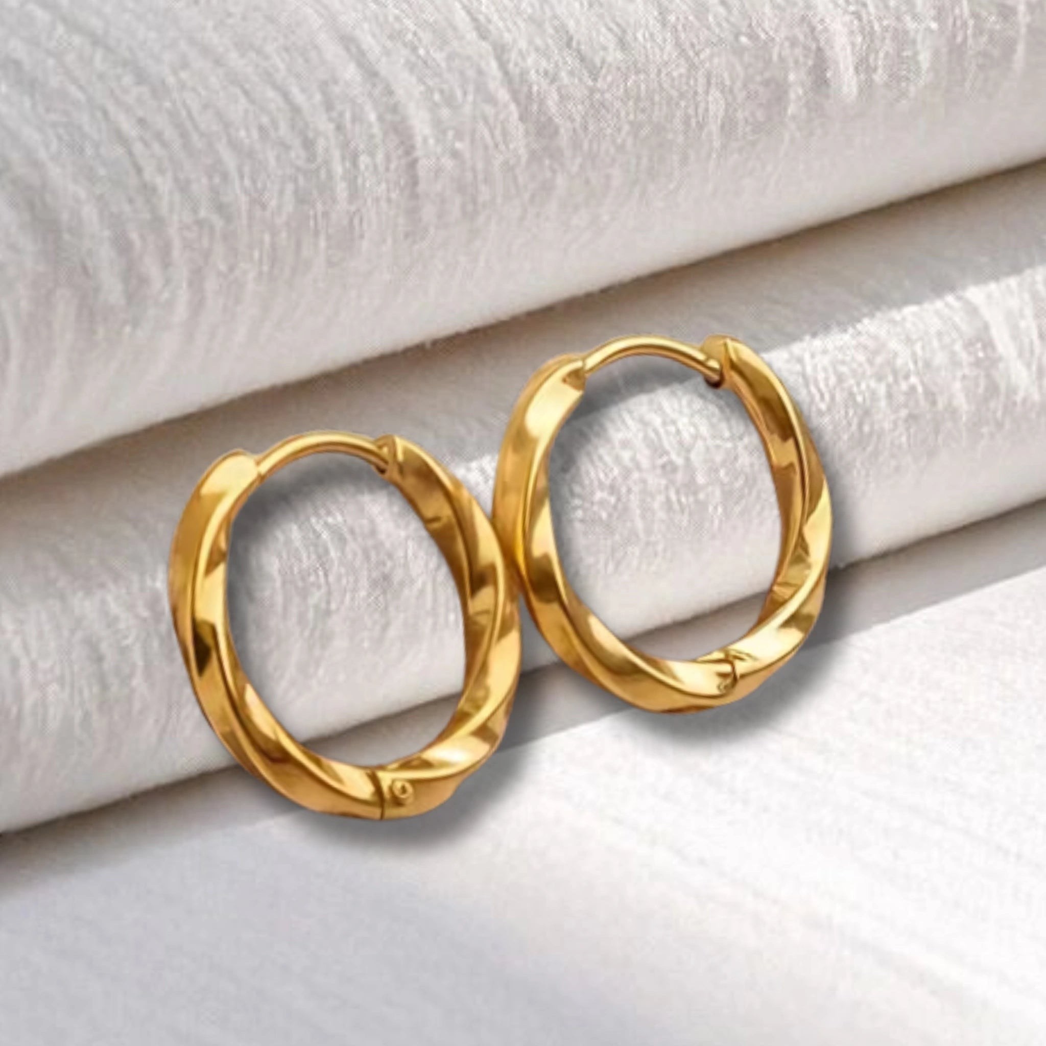 créoles torsadées en acier inoxydables dorées posées sur un linge