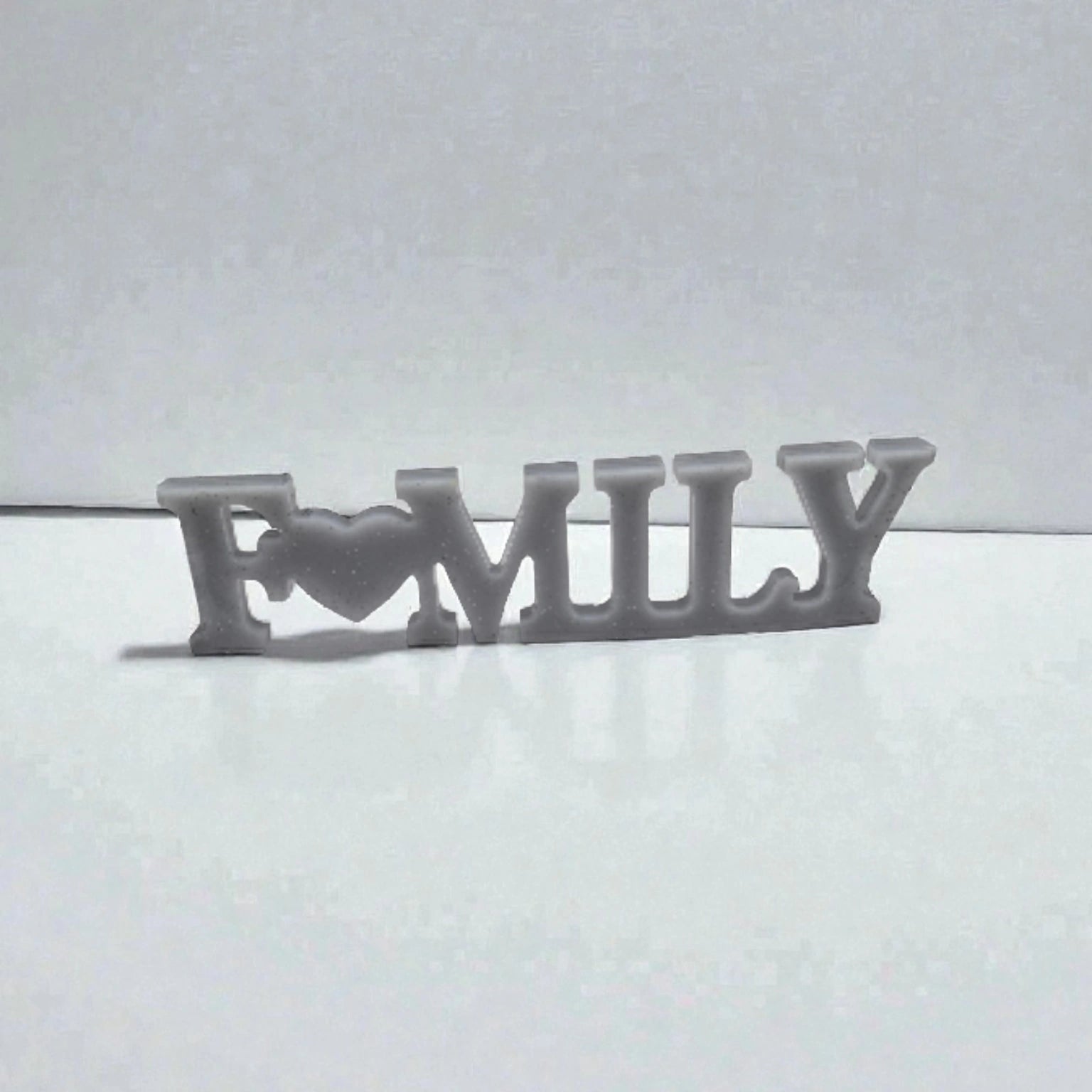 Décoration intérieure Family en résine pailletée argentée posée sur surface plane neutre