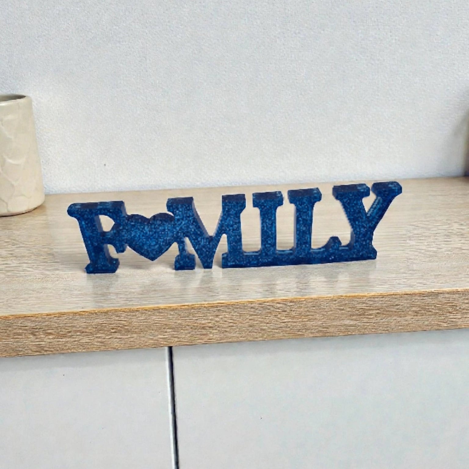 Décoration intérieure Family en résine pailletée bleue posée sur surface plane neutre