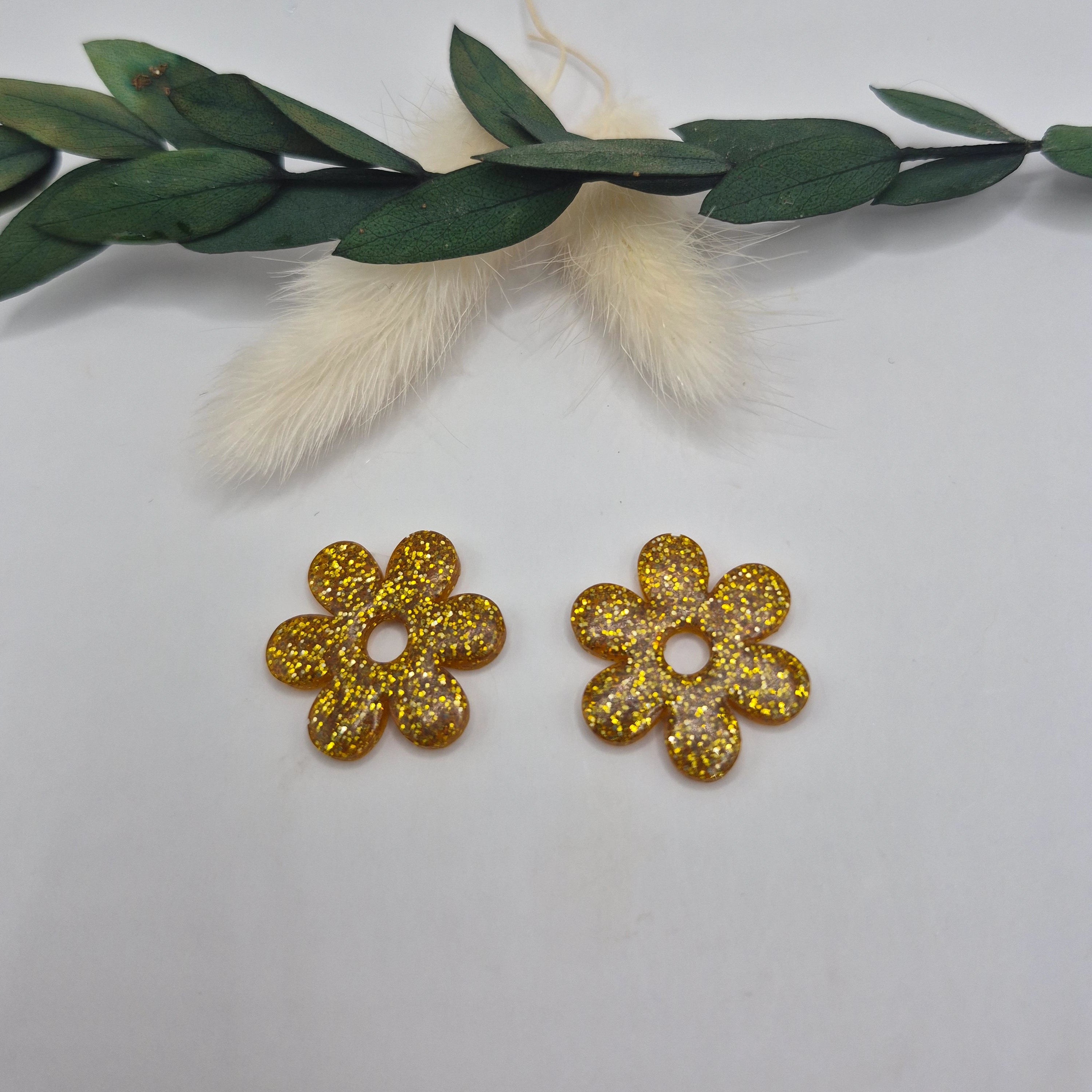 Pampilles dorées Marjorie résine pailletée posées à plat avec branche verte et pampa en fond de décor