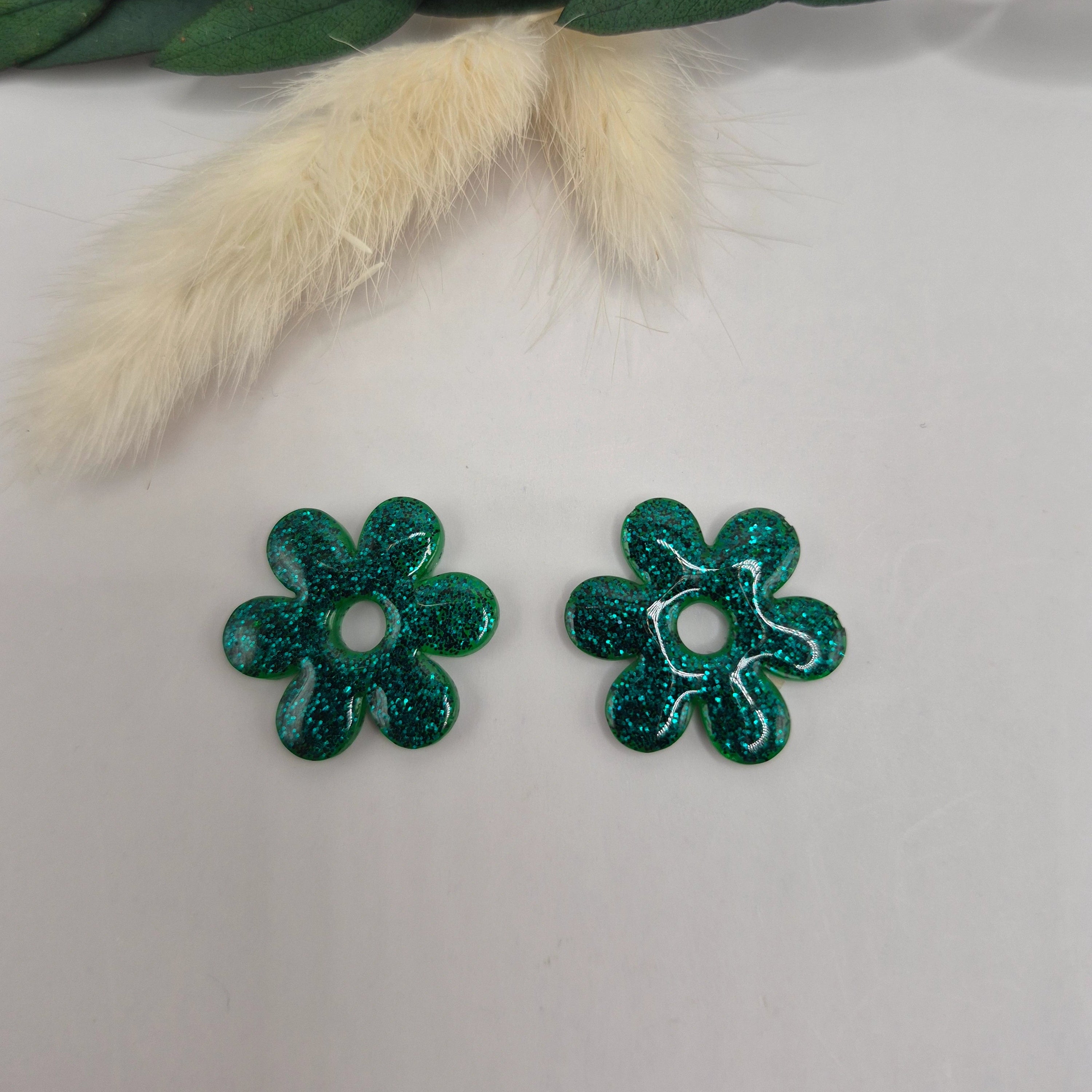 Pampilles vertes Marjorie résine pailletée posées à plat avec branche verte et pampa en fond de décor