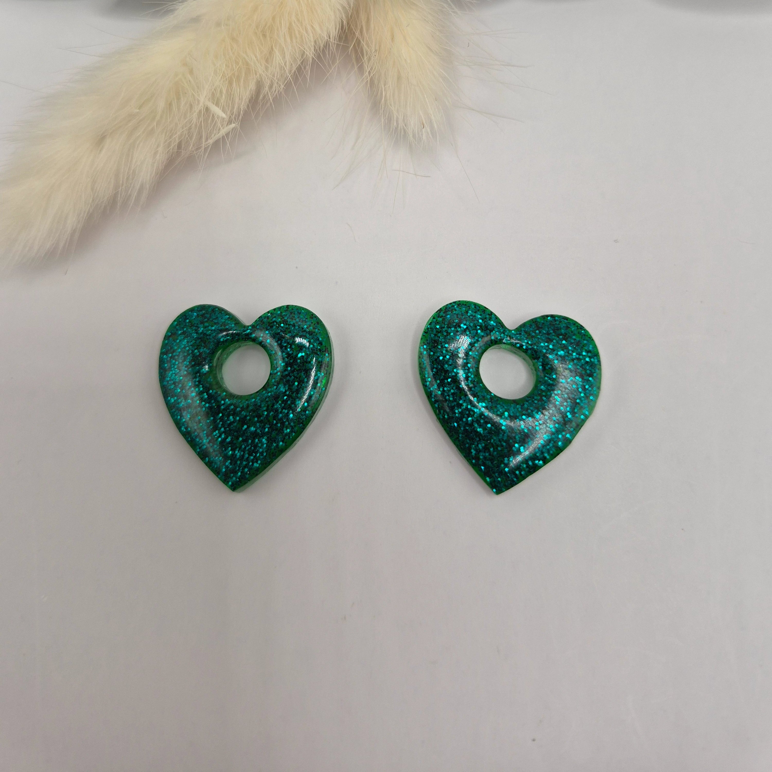 Pampilles Coralie vertes résine pailletée posées à plat avec branche verte et pampa en fond de décor