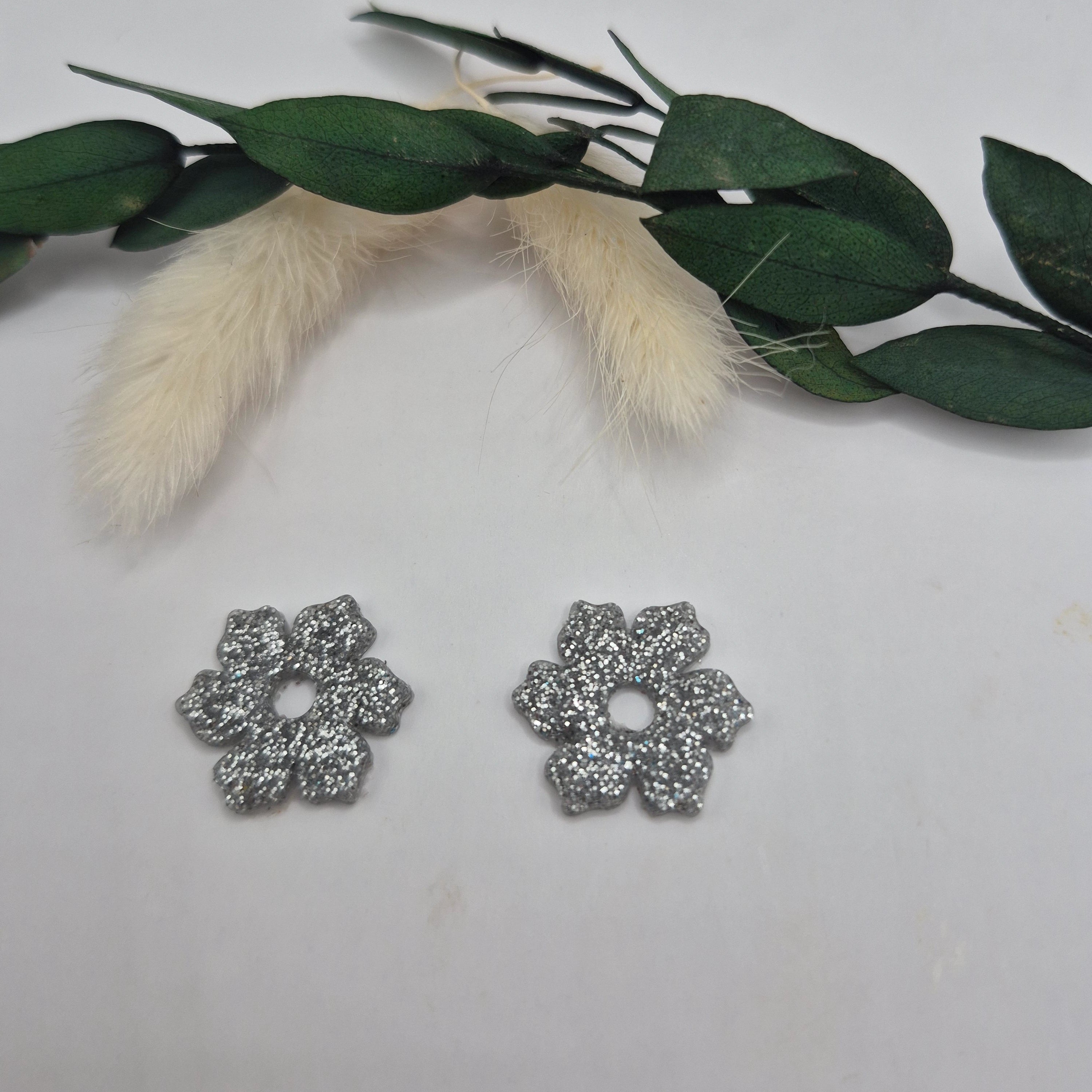 Pampilles Elodie fleur 5 pétales argentées en résine  posées à plat, décor pampa et feuilles vertes