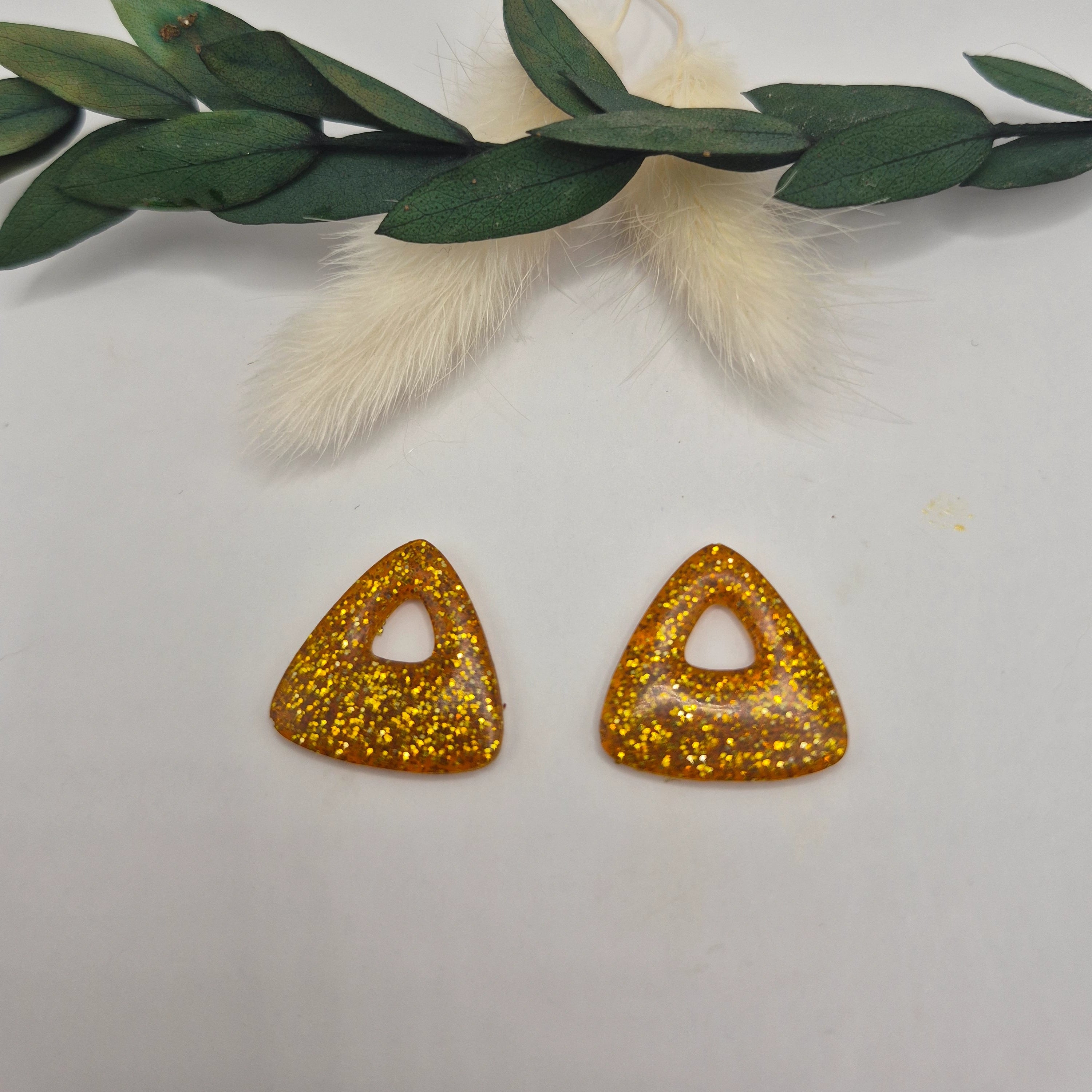 Pampilles Julie dorées résine pailleté posées à plat avec branche verte et pampa en fond de décor