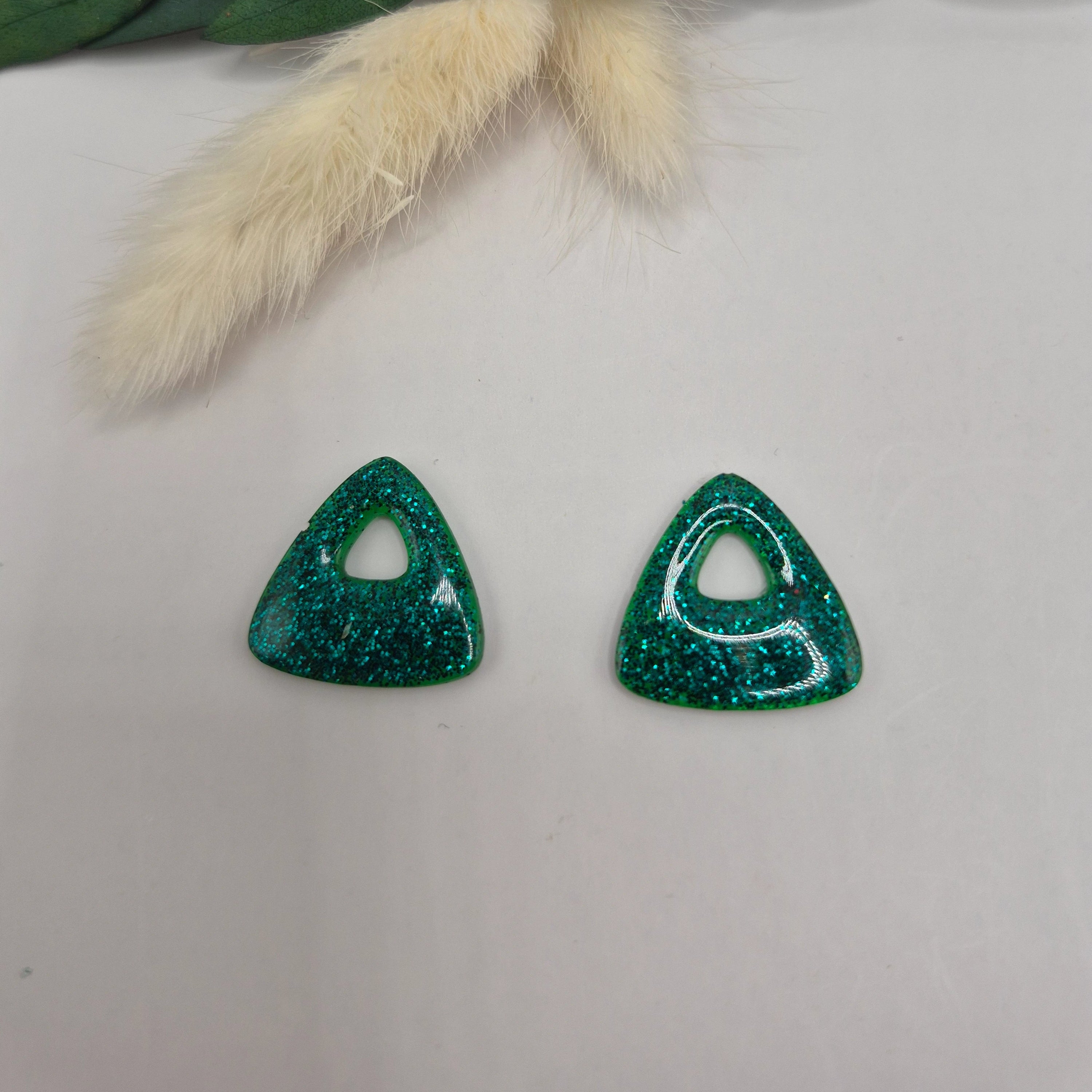 Pampilles Julie vertes résine pailleté posées à plat avec branche verte et pampa en fond de décor