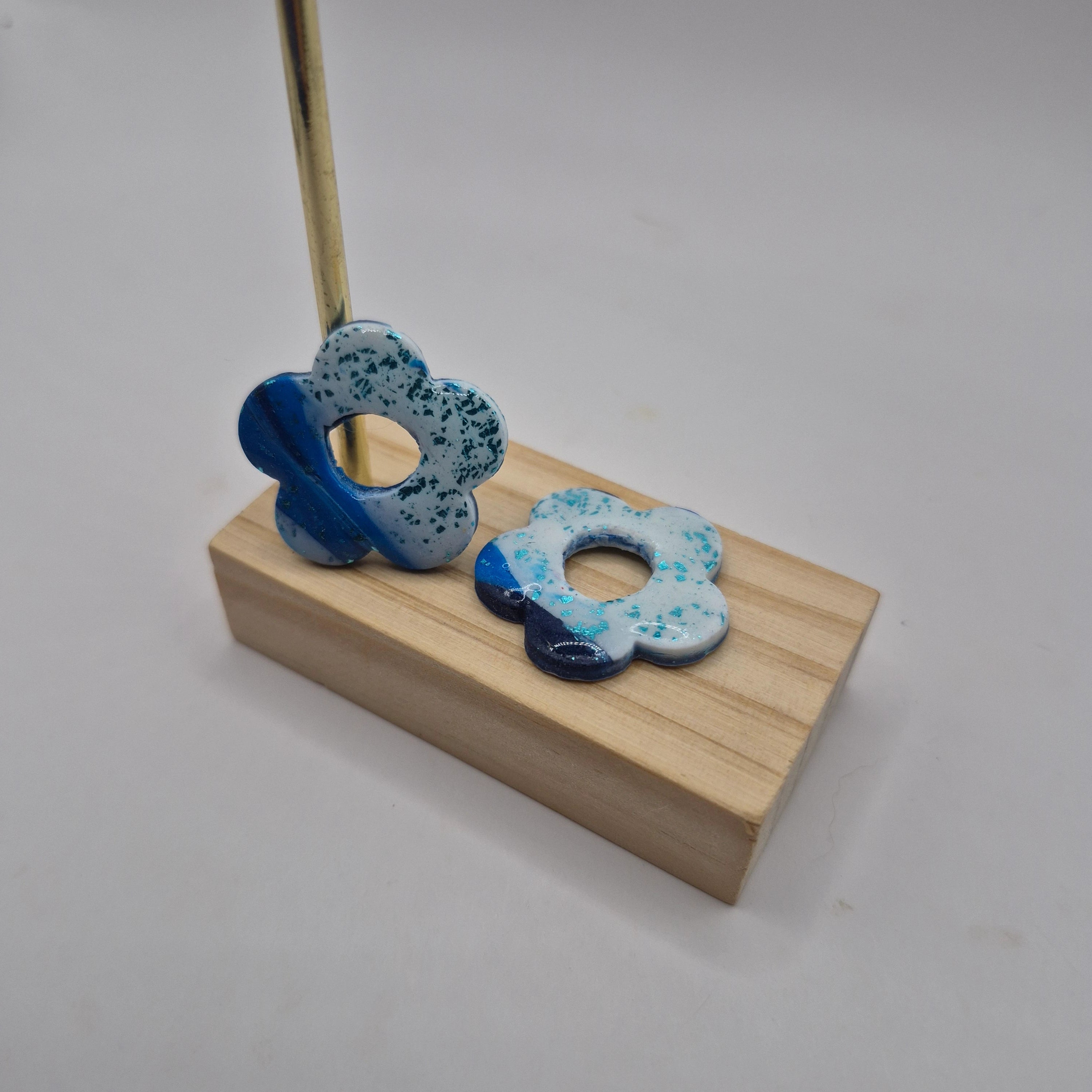 Pampilles fleur bleue  en pâte polymère pour boucles d’oreilles interchangeables  – accessoires créatifs faits main pour bijoux artisanaux, présentés sur un support en bois.