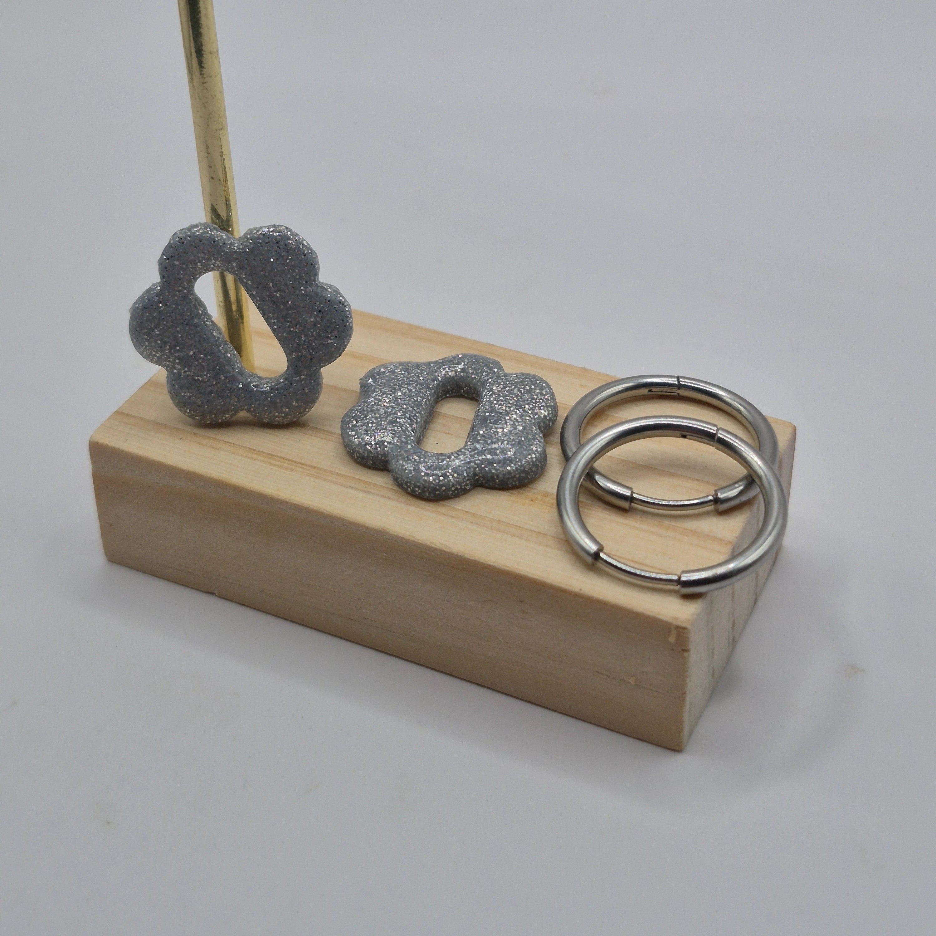 Parure Sophie : pampilles interchangeables en pâte polymère argentée pailletée, en forme de fleur nuage, présentées sur un support en bois, avec 2 créoles argentées en acier inoxydables.