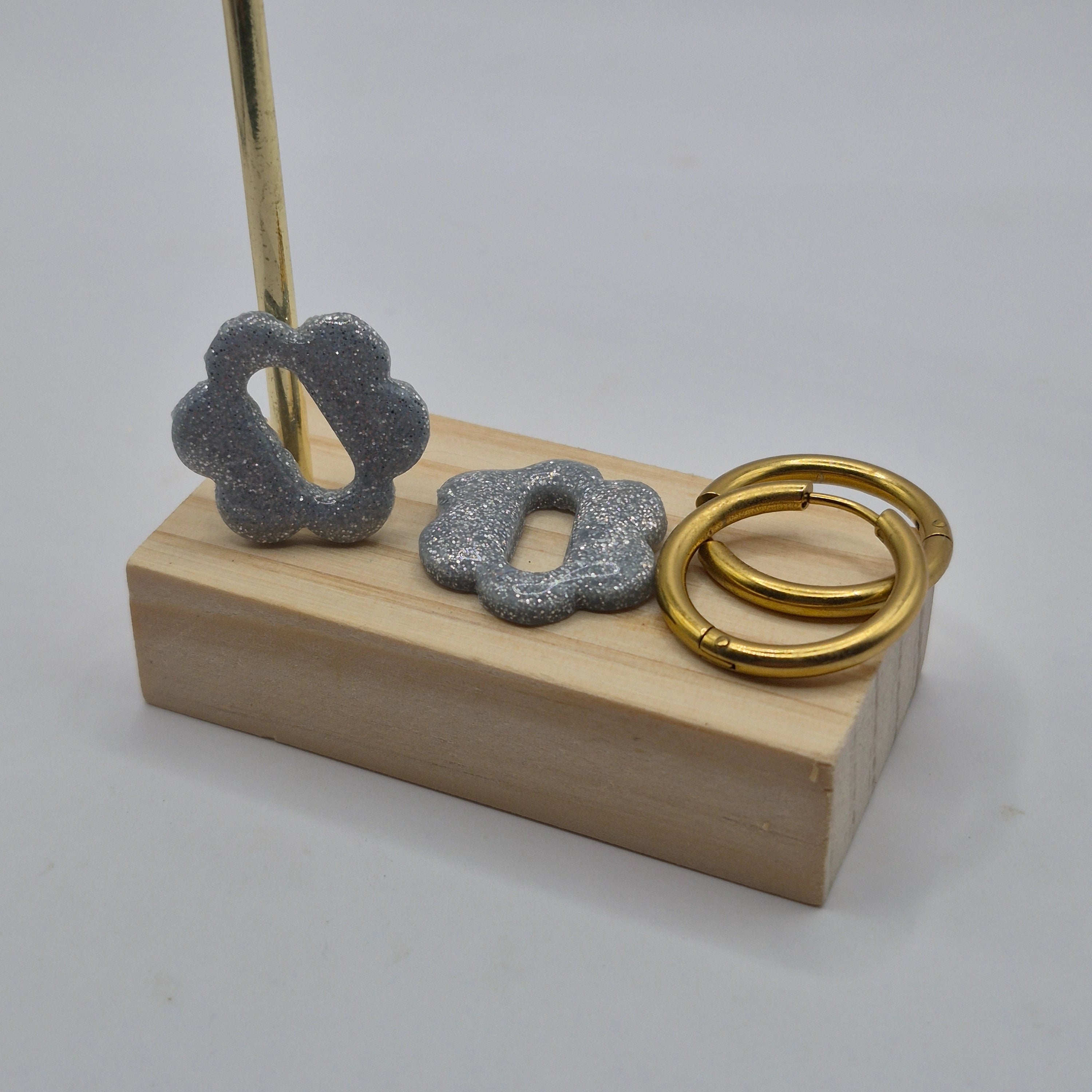 Parure Sophie : pampilles interchangeables en pâte polymère argentée pailletée, en forme de fleur nuage, présentées sur un support en bois, avec 2 créoles dorées en acier inoxydables.