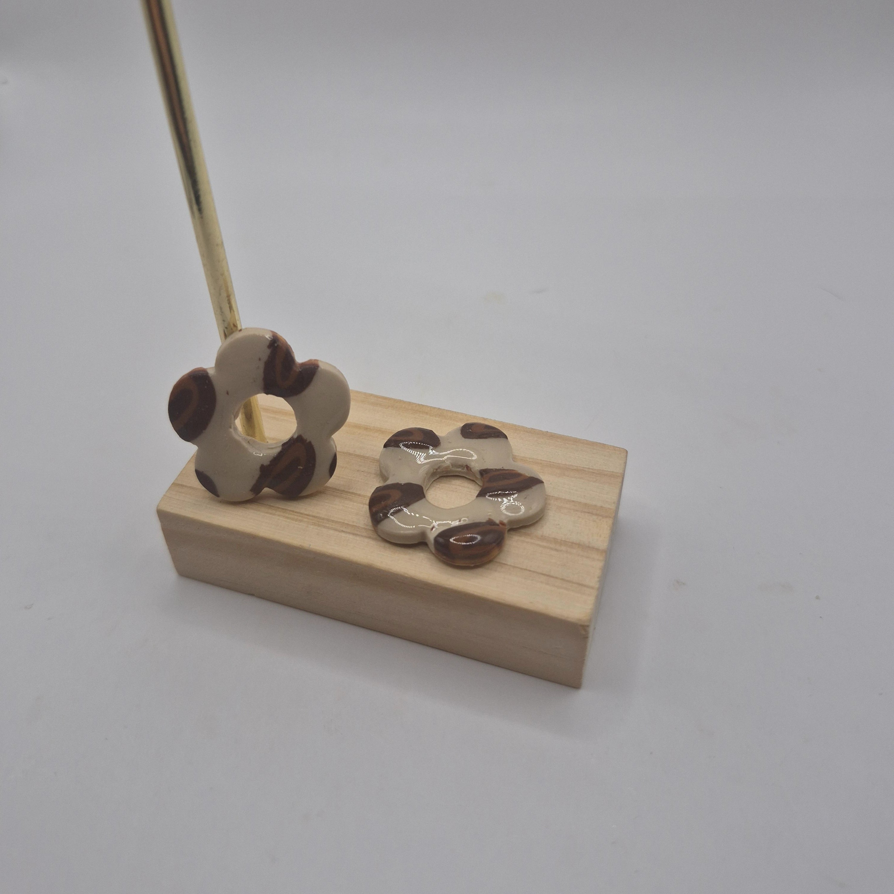 Pampilles fleur motif léopard marron et beige en pâte polymère pour boucles d’oreilles interchangeables – accessoires créatifs faits main pour bijoux artisanaux, présentés sur un support en bois.