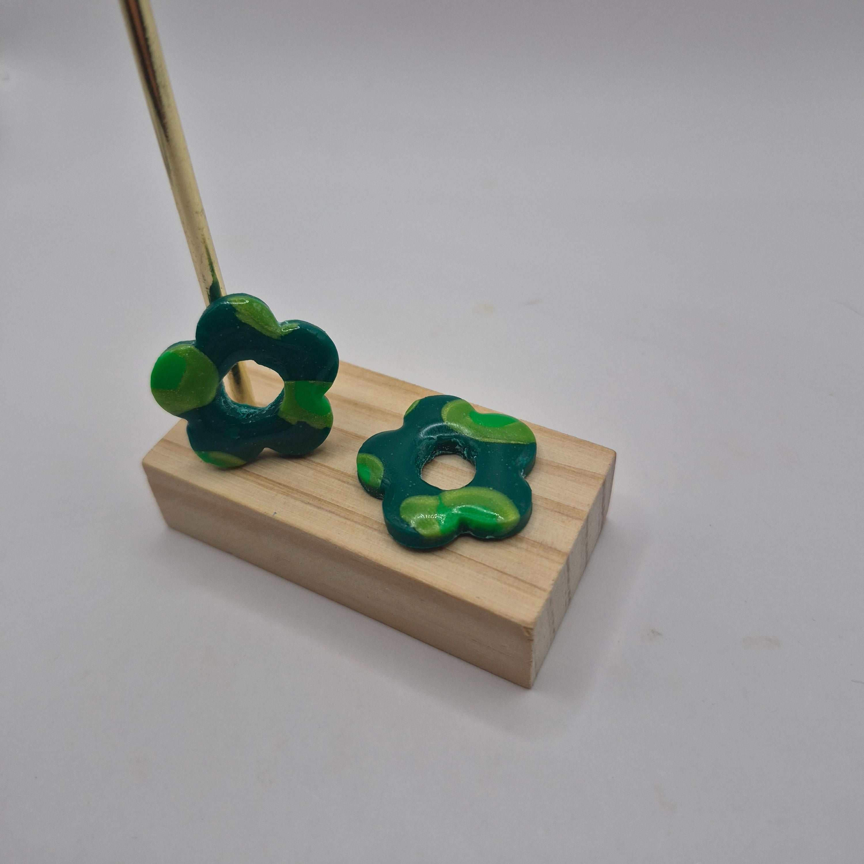 Pampilles fleur vert en pâte polymère pour boucles d’oreilles interchangeables – accessoires créatifs faits main pour bijoux artisanaux, présentés sur un support en bois.