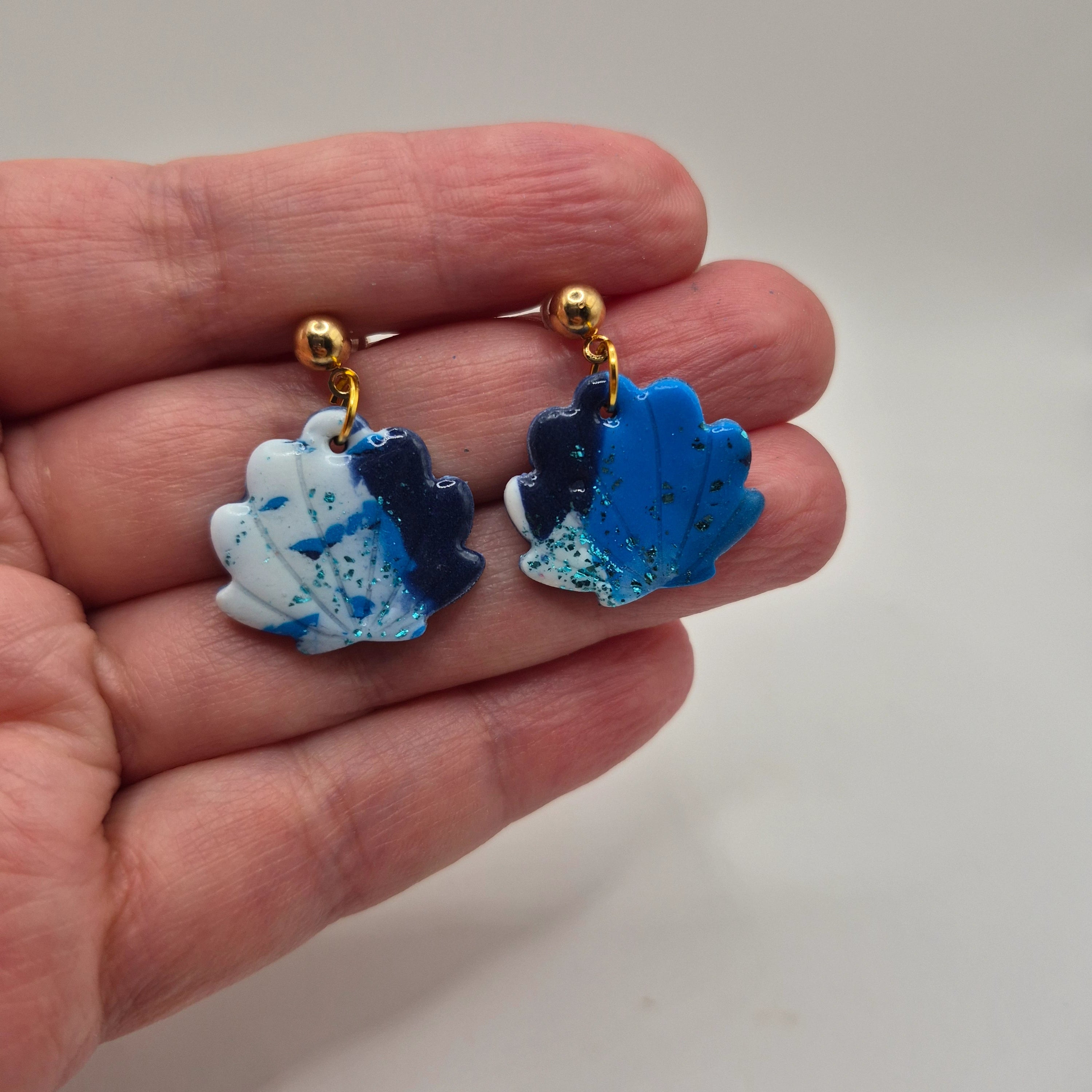 Boucles d’oreilles coquillage en pâte polymère bleu et blanc faites main, finition résine et attaches en acier inoxydable doré — parure Julia artisanale.
