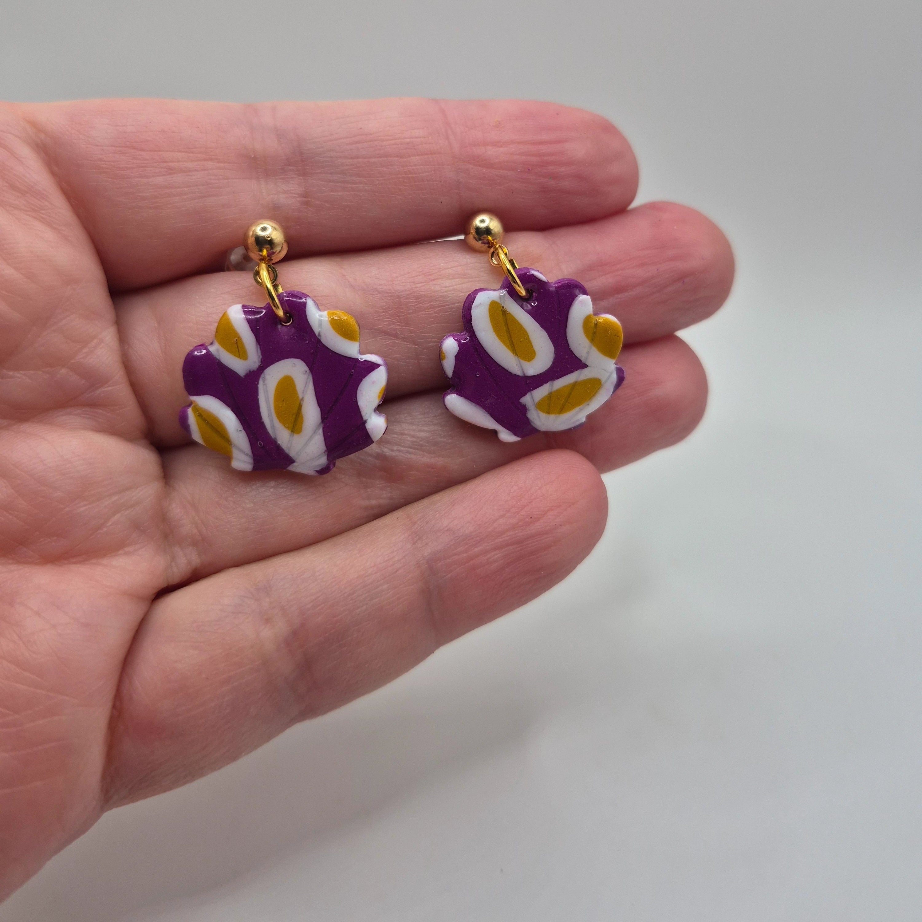 Boucles d’oreilles coquillage en pâte polymère violet, blanc et ocre faites main, finition résine et attaches en acier inoxydable doré — parure Julia artisanale.