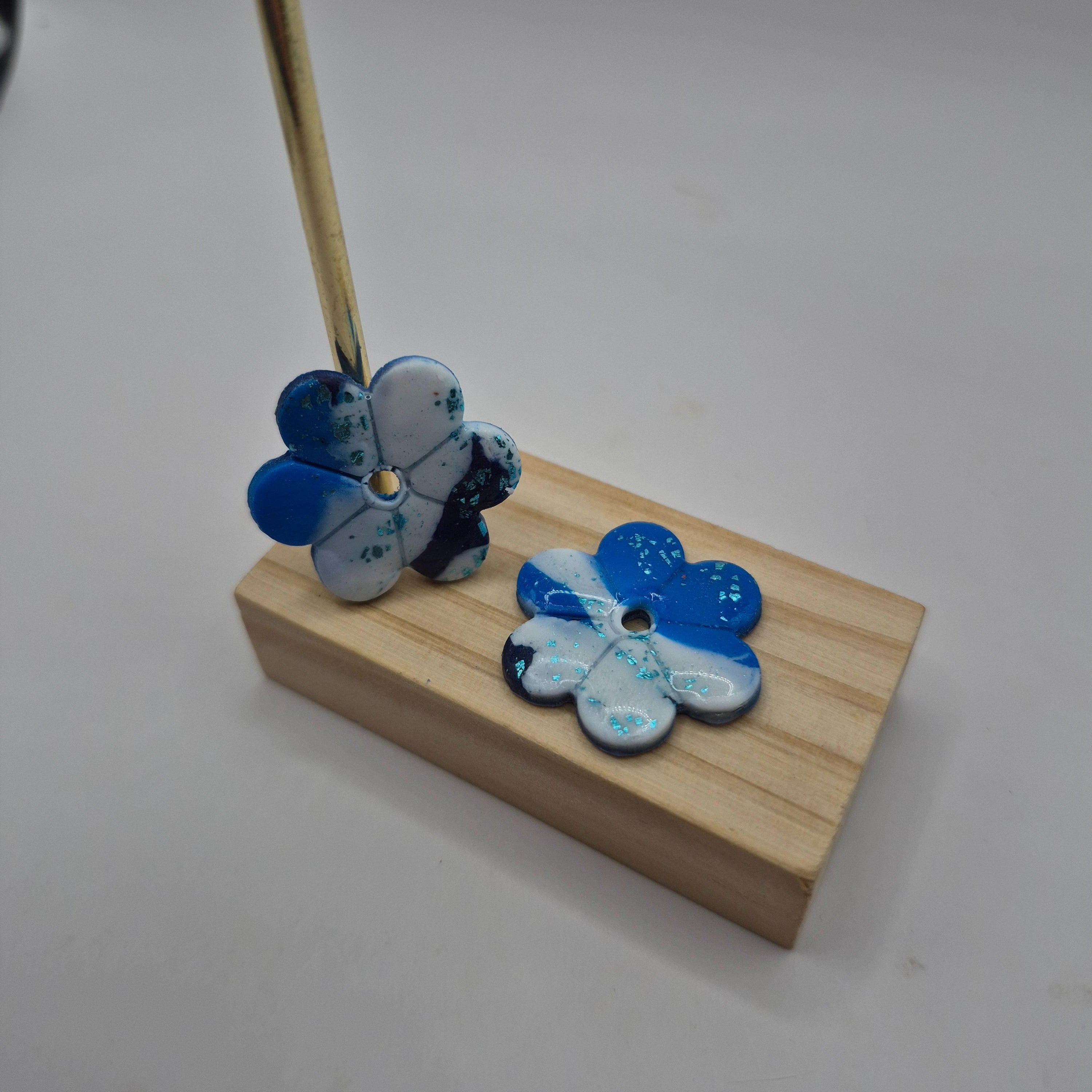 Boucles d’oreilles pampilles fleur en pâte polymère bleu et blanc faites main, finition résine présentées sur un support en bois— parure Lilia artisanale.