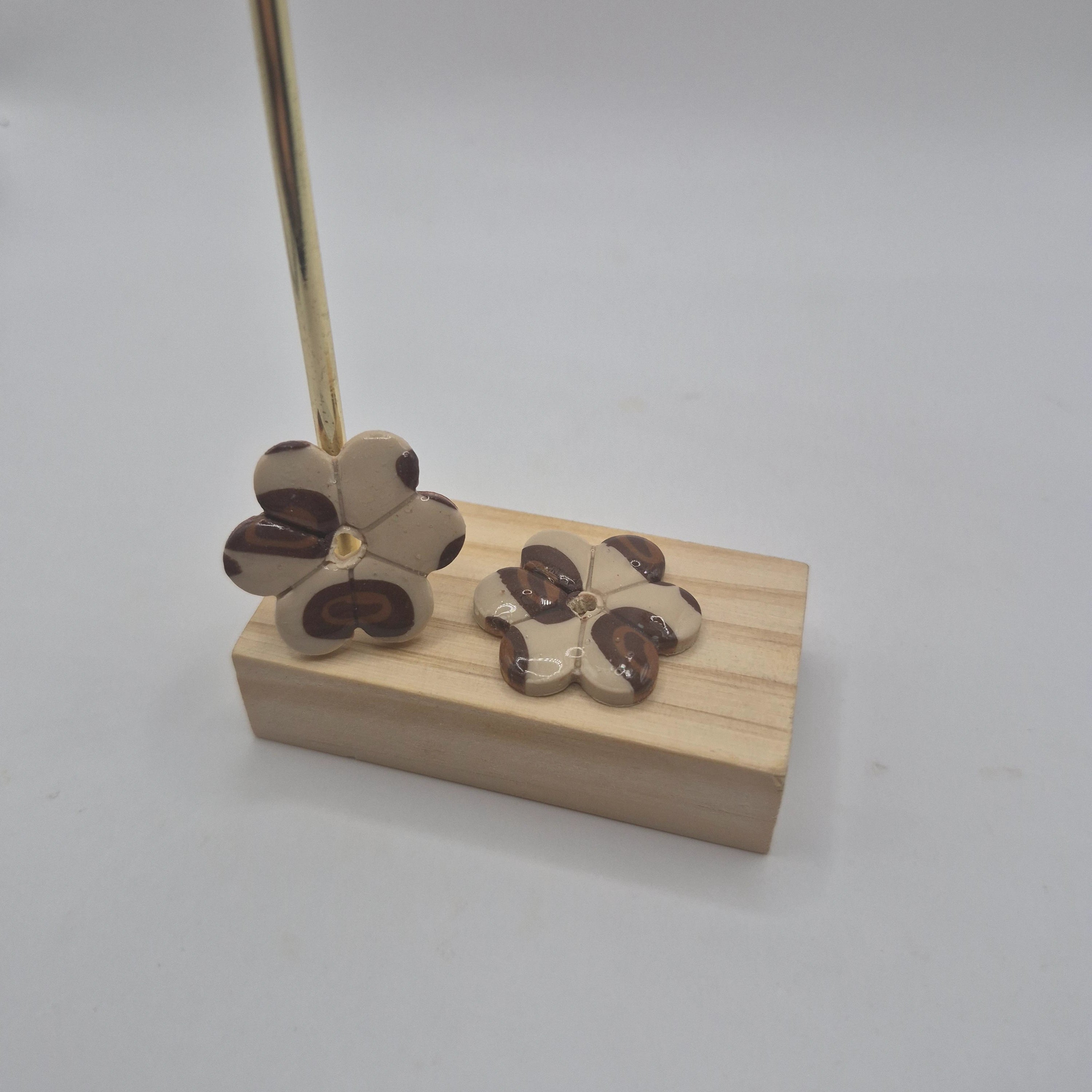 Boucles d’oreilles pampilles fleur en pâte polymère motif léopard marron et beige faites main, finition résine présentées sur un support en bois — parure Lilia artisanale.