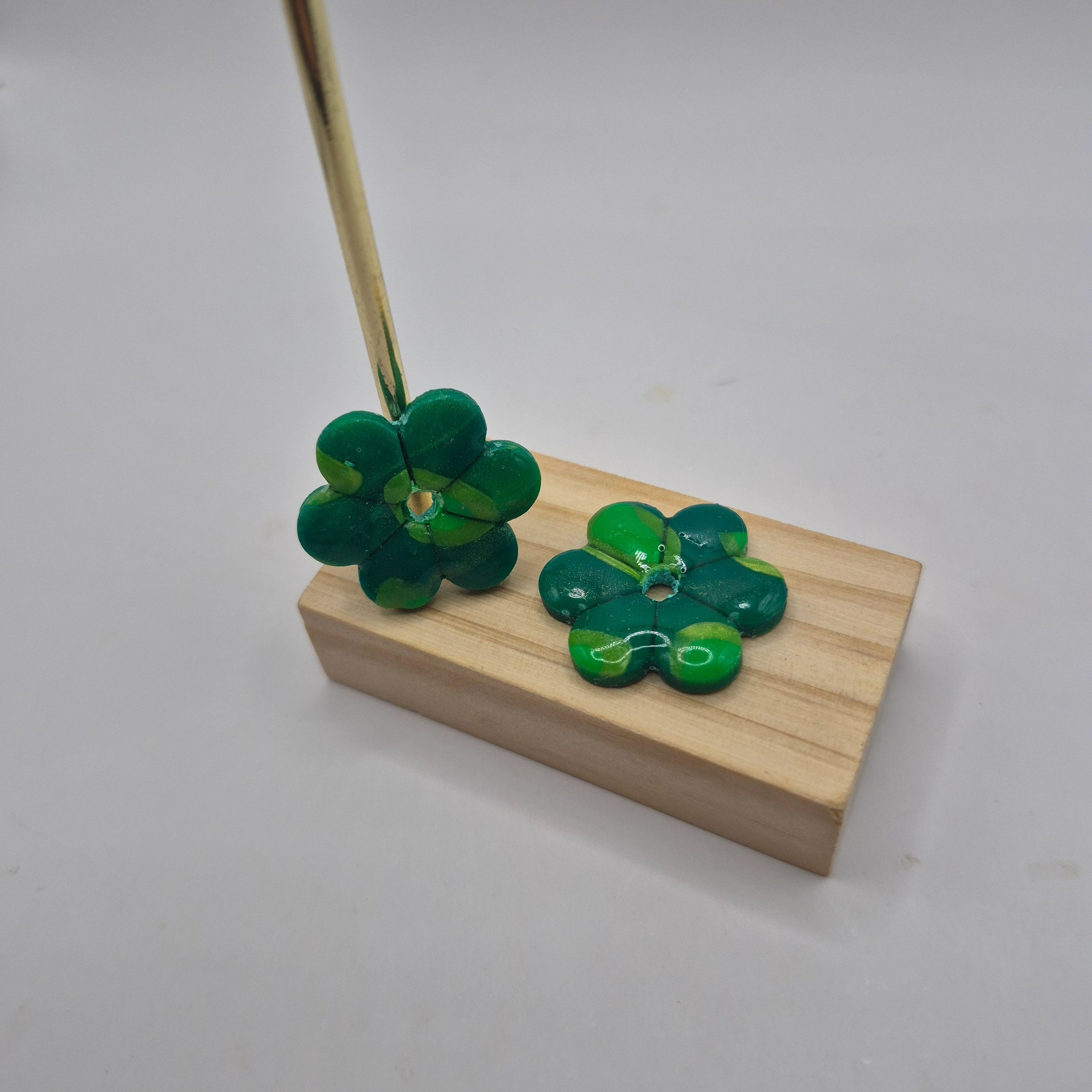 Boucles d’oreilles pampilles fleur en pâte polymère vert faites main, finition résine présentées sur un support en bois — parure Lilia artisanale.