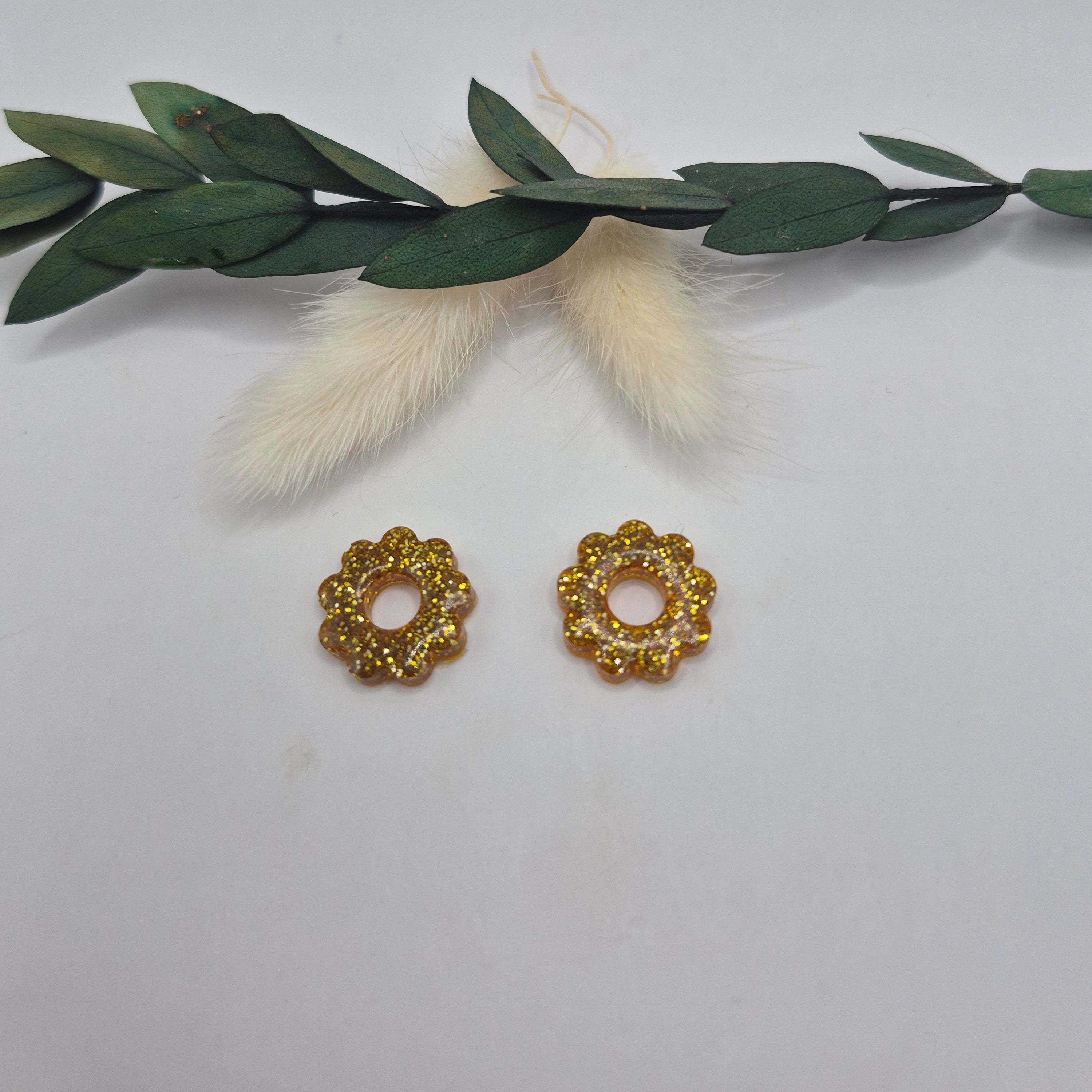 Pampilles dorées résine pailleté posées à plat avec branche verte et pampa en fond de décor