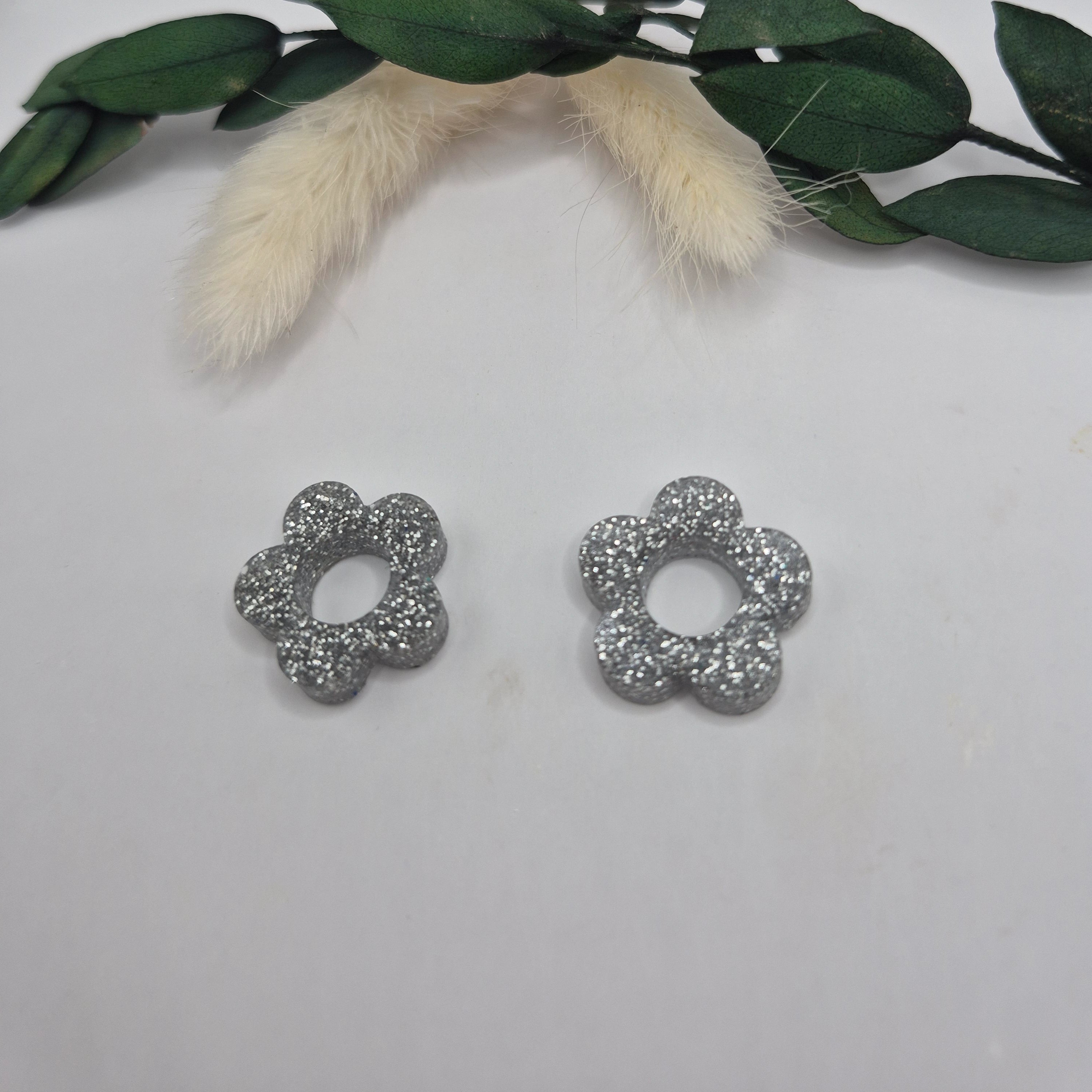 Pampilles Lexie argentées résine pailletée posées à plat avec branche verte et pampa en fond de décor