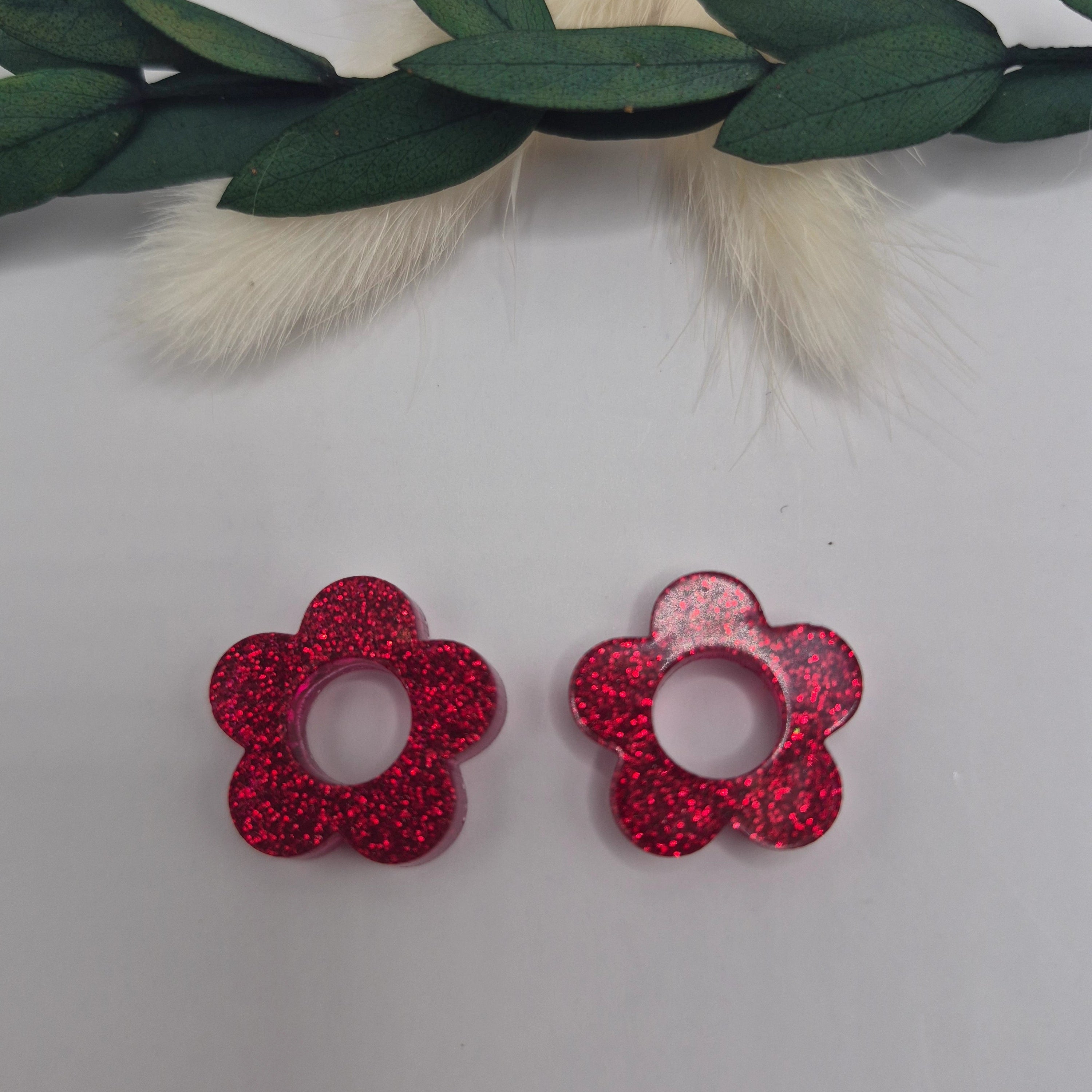 Pampilles Lexie rouges résine posées à plat avec branche verte et pampa en fond de décor