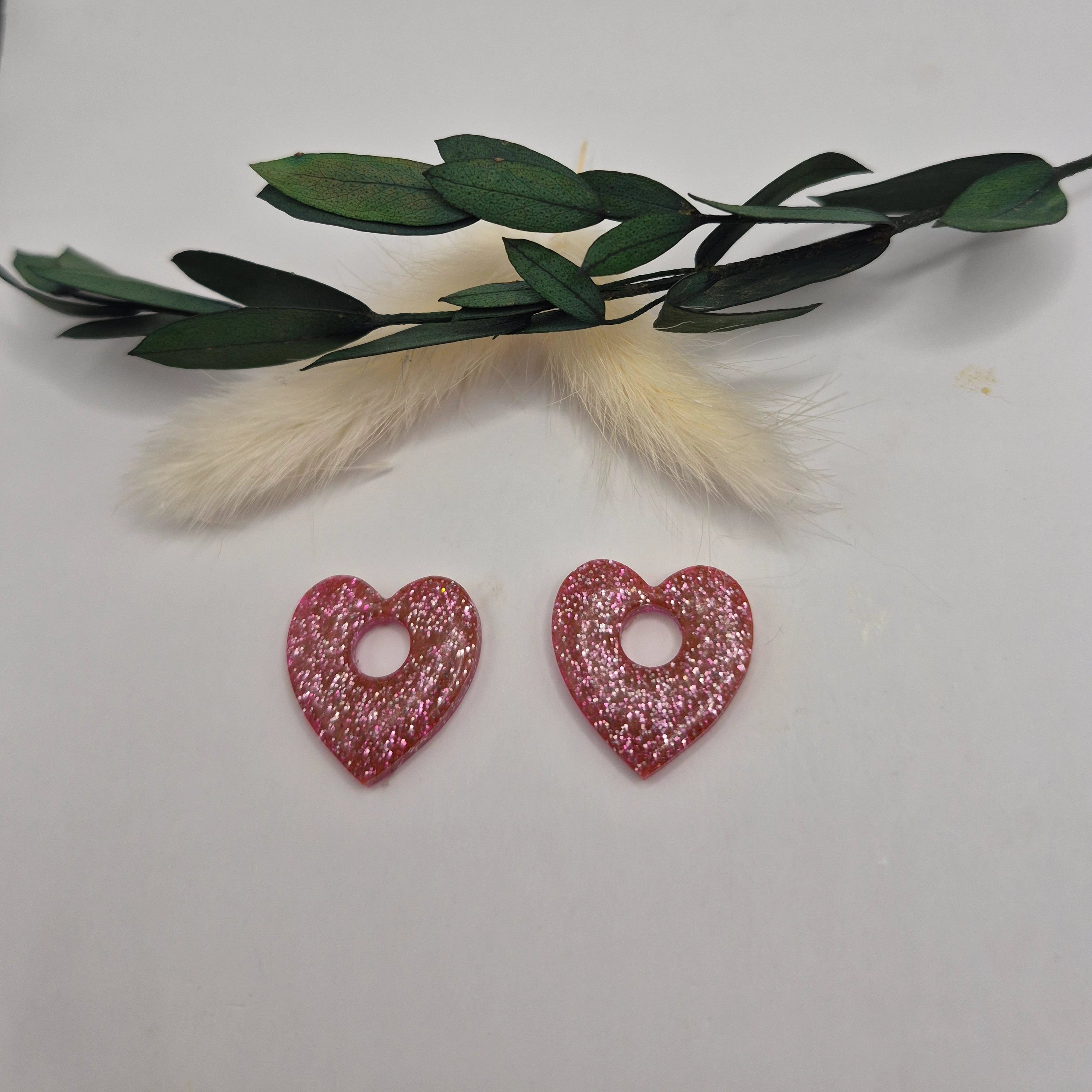 Pampilles Coralie roses résine pailleté posées à plat avec branche verte et pampa en fond de décor