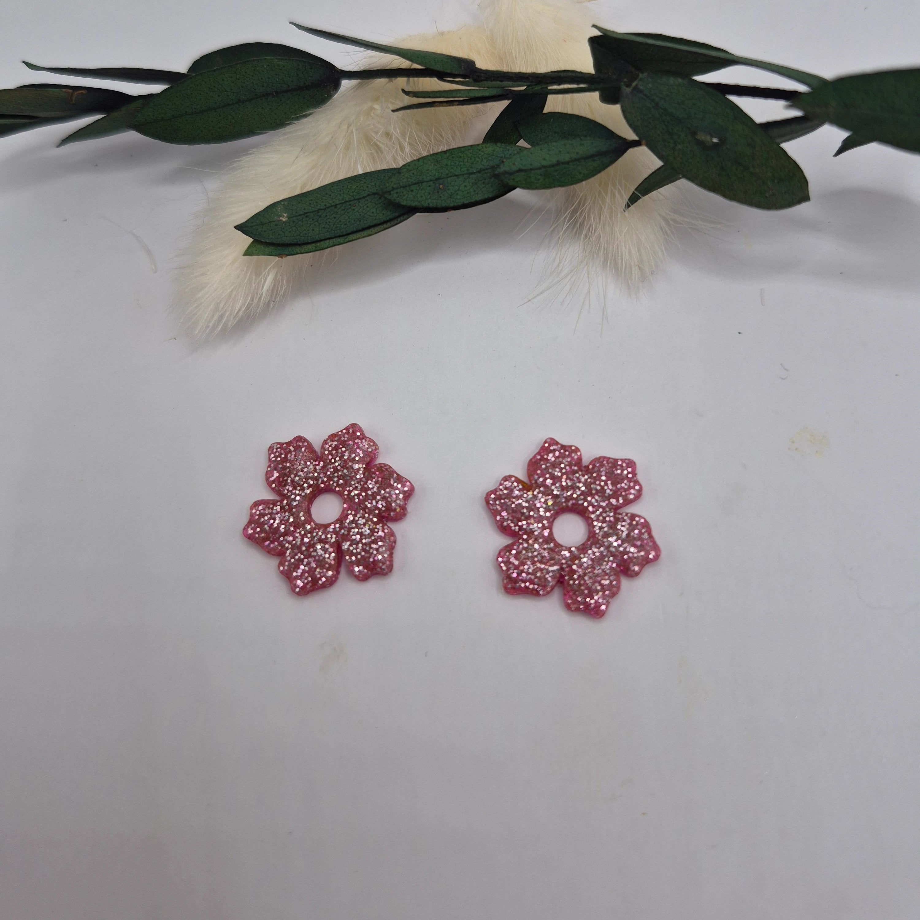 Pampilles Elodie fleur 5 pétales roses en résine posées à plat, décor pampa et feuilles vertes