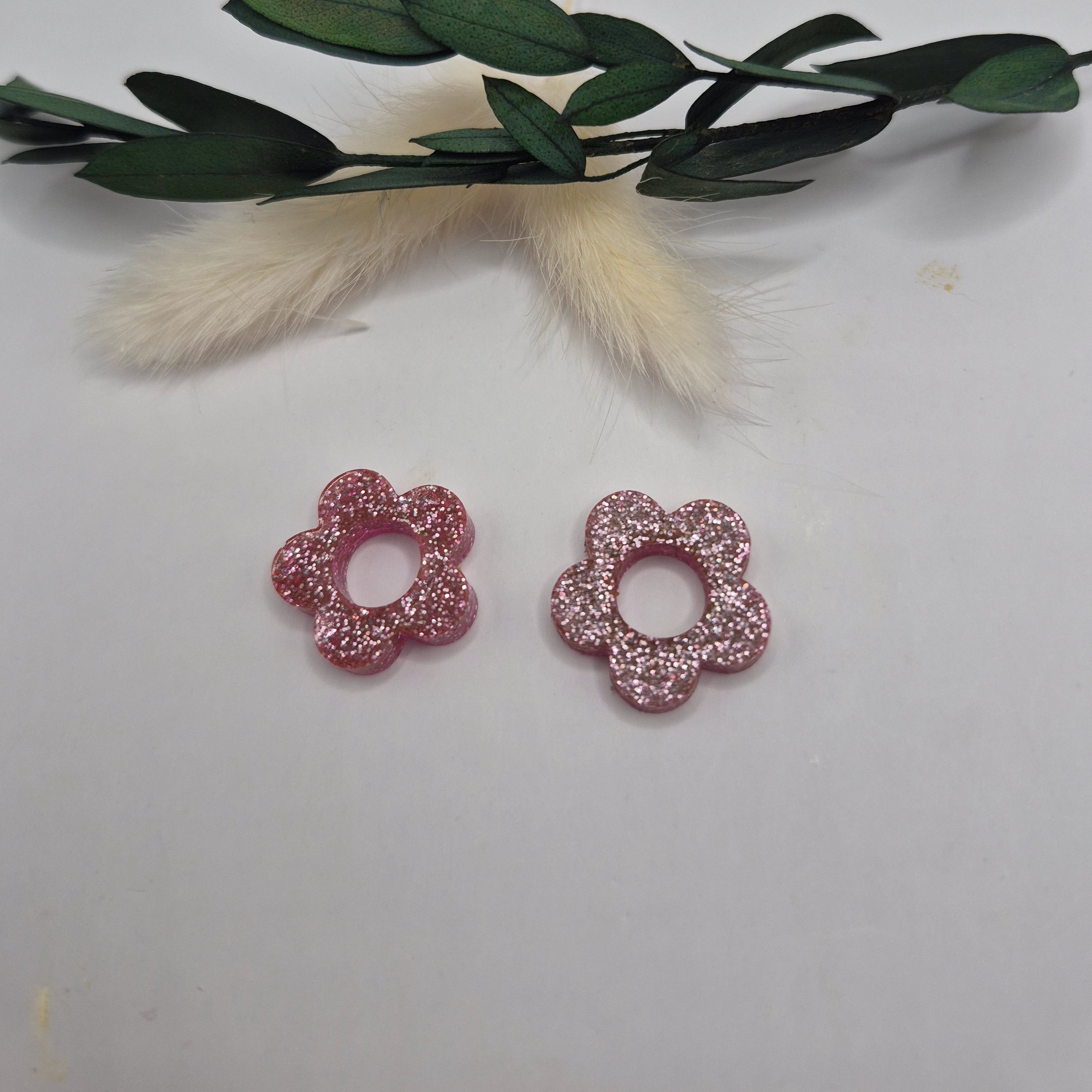 Pampilles Lexie roses résine pailletée posées à plat  avec branche verte et pampa en fond de décor