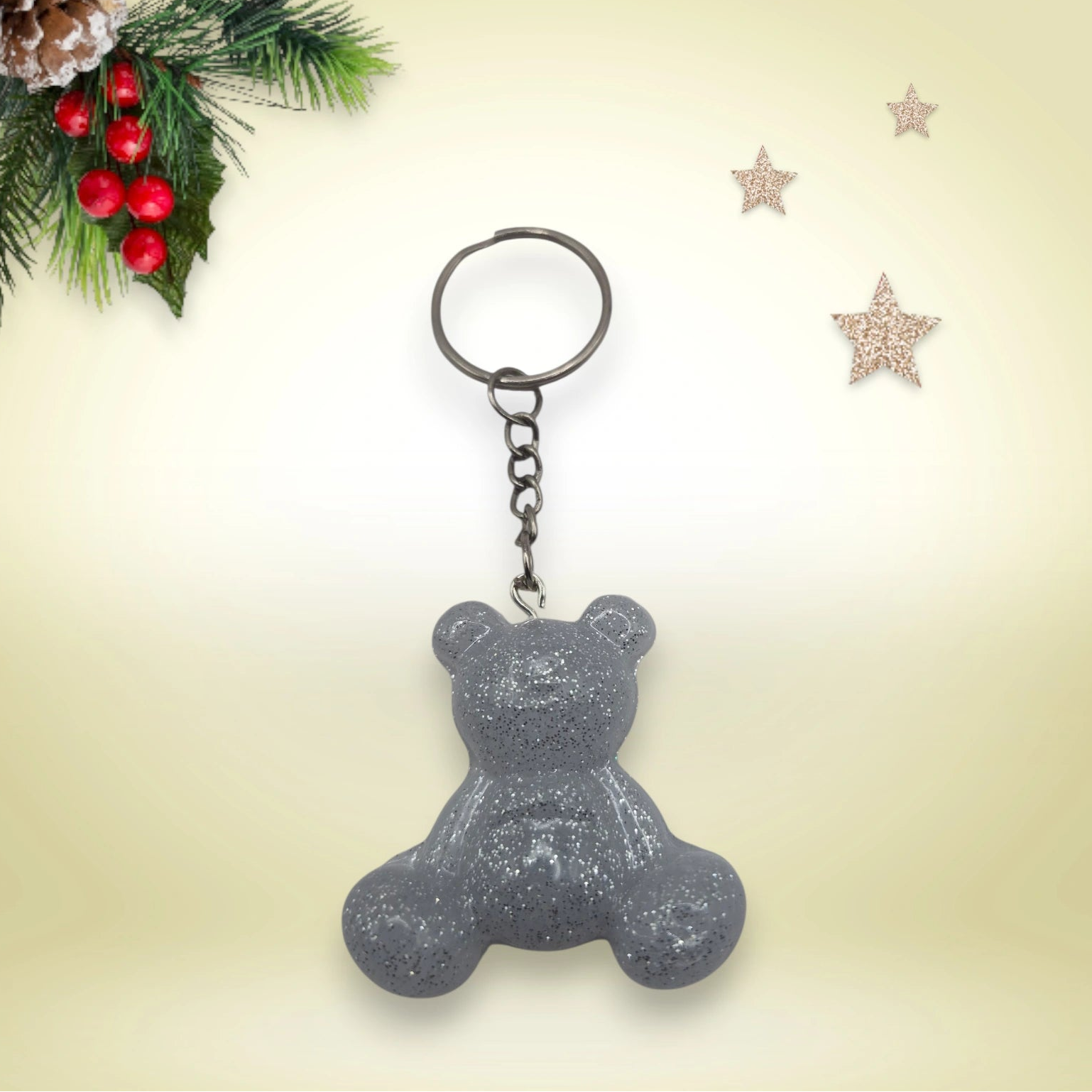 gris pailletée, avec anneau argenté, posé sur un fond orné de branches de sapin et d’étoiles décoratives.