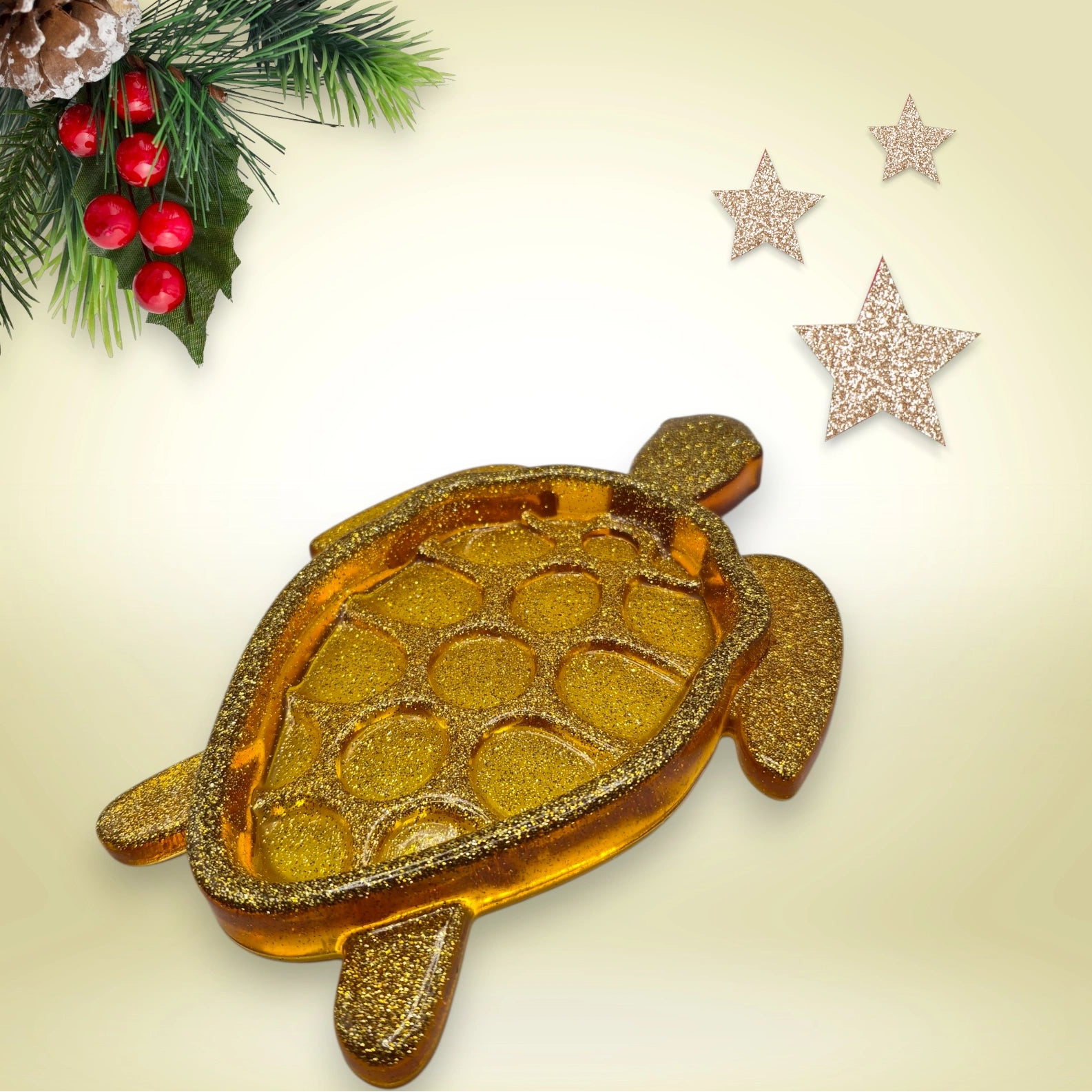 Vide-poche en résine pailletée dorée, en forme de tortue, décoré d’un fond agrémenté de branches de sapin et d’étoiles scintillantes.