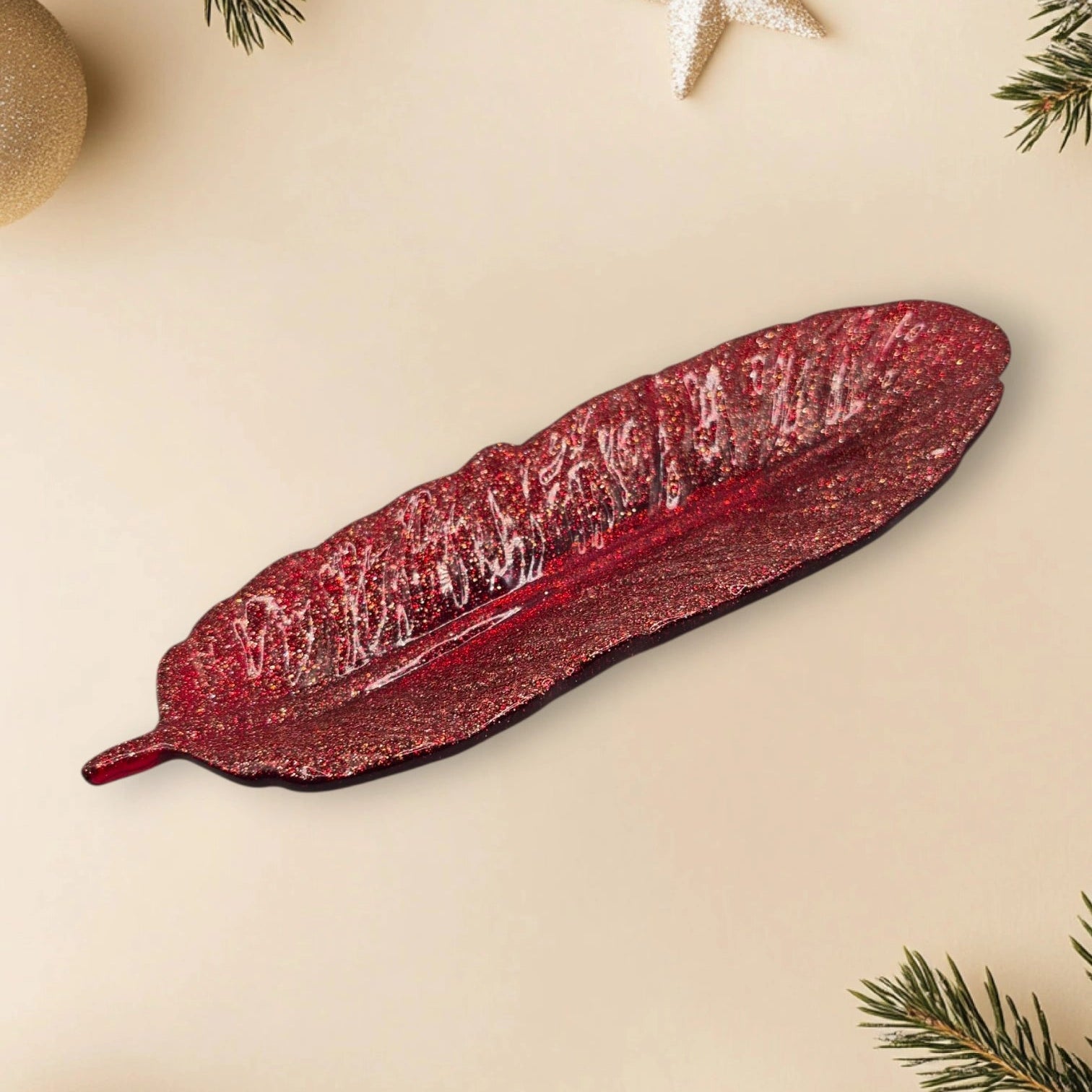 vide-poche en forme de plume en résine pailletée rouge posée sur un fond décoratif