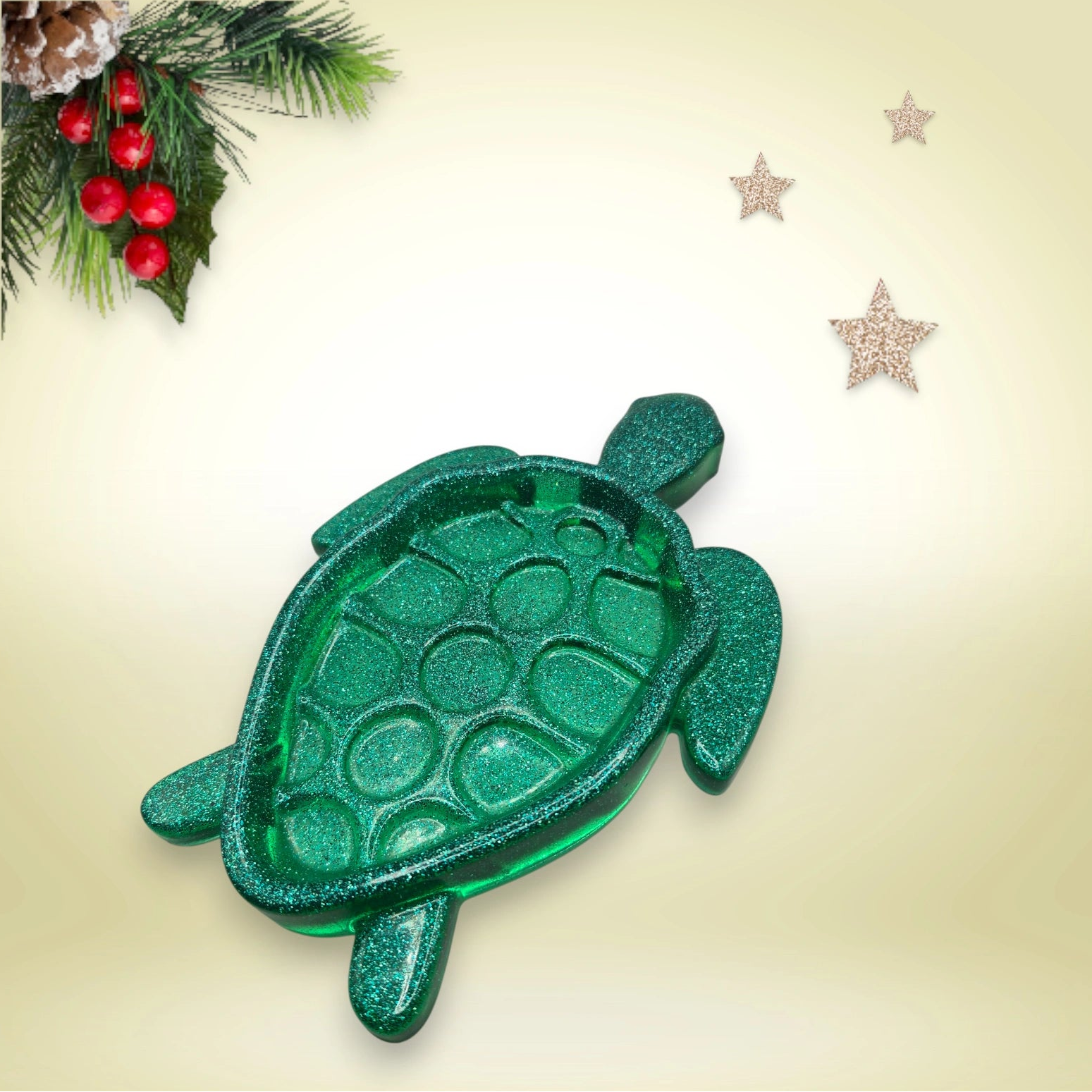 Vide-poche en résine pailletée verte foncée, en forme de tortue, décoré d’un fond agrémenté de branches de sapin et d’étoiles scintillantes.