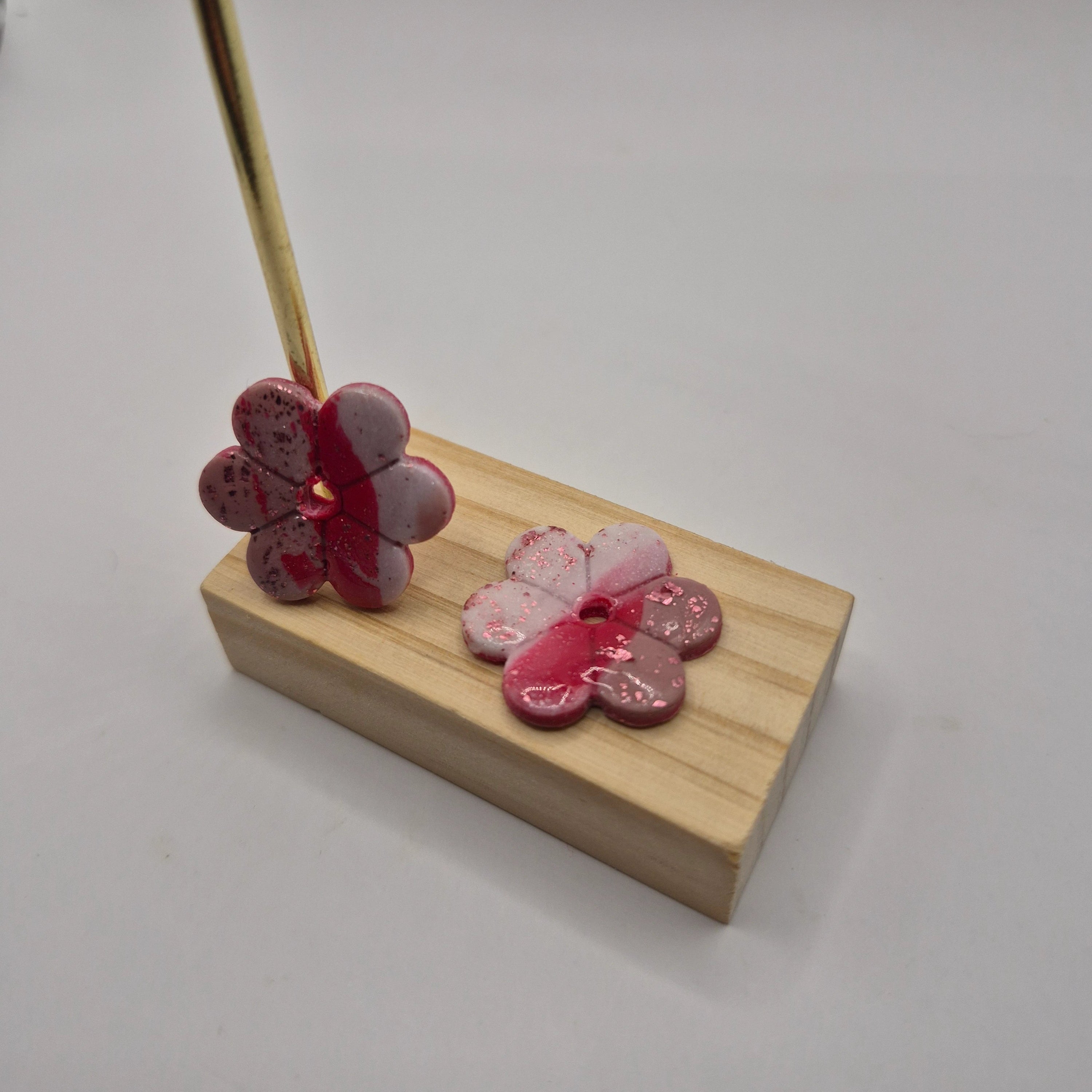 Boucles d’oreilles pampilles fleur en pâte polymère rose faites main, finition résine présentées sur un support en bois — parure Lilia artisanale.